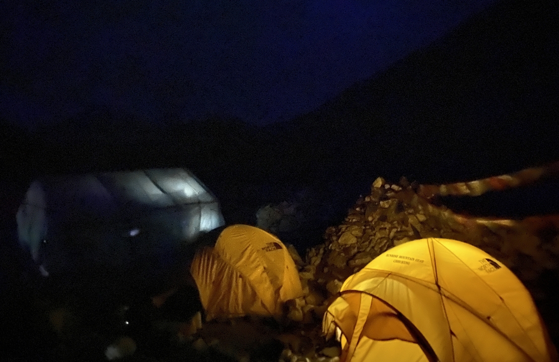 Campement de nuit avec des tentes illuminées.