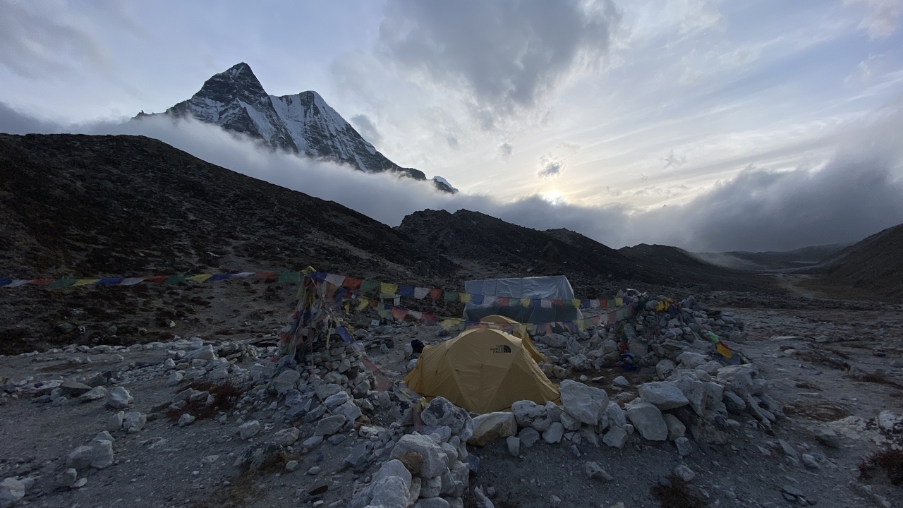 Un campement de tentes installé au milieu d'un terrain montagneux au crépuscule.