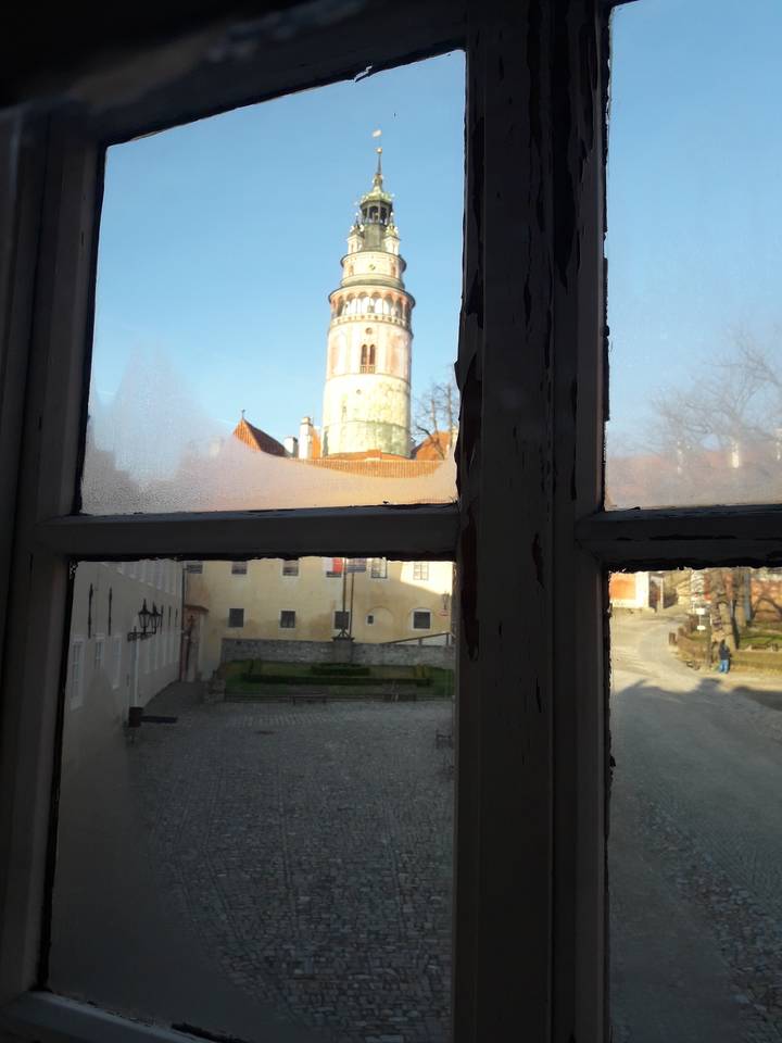 Vue à travers une fenêtre d'une ville historique avec une tour.