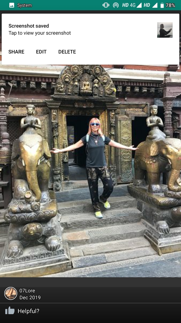 Femme posant avec des statues d'éléphants décoratifs à l'entrée d'un temple.