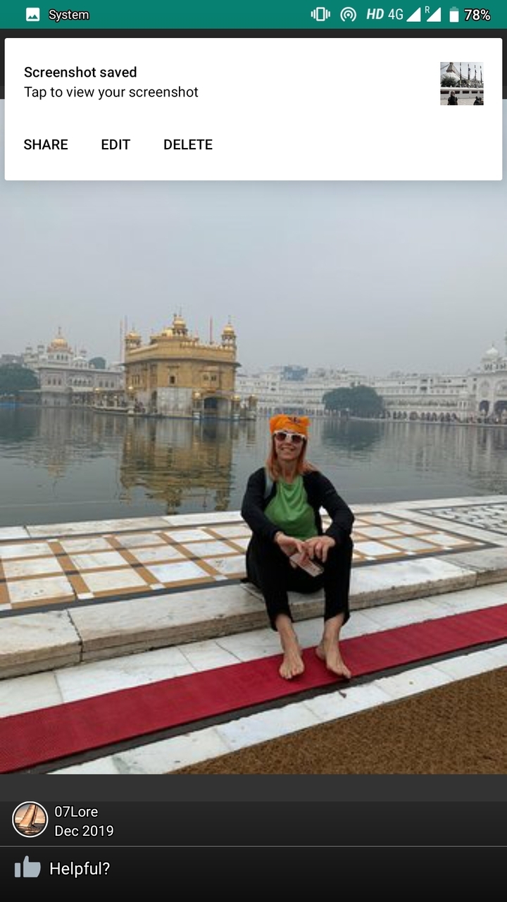 Femme assise près d'un plan d'eau avec un temple en arrière-plan.