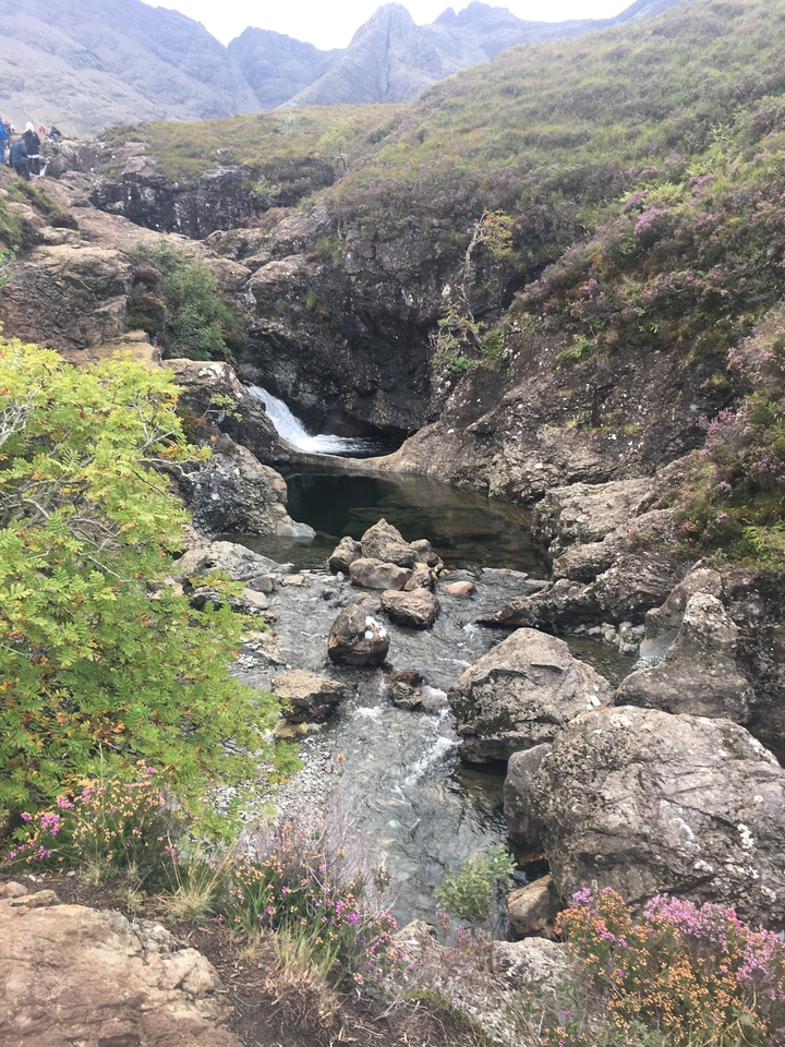 Un ruisseau rocheux avec une cascade en arrière-plan.