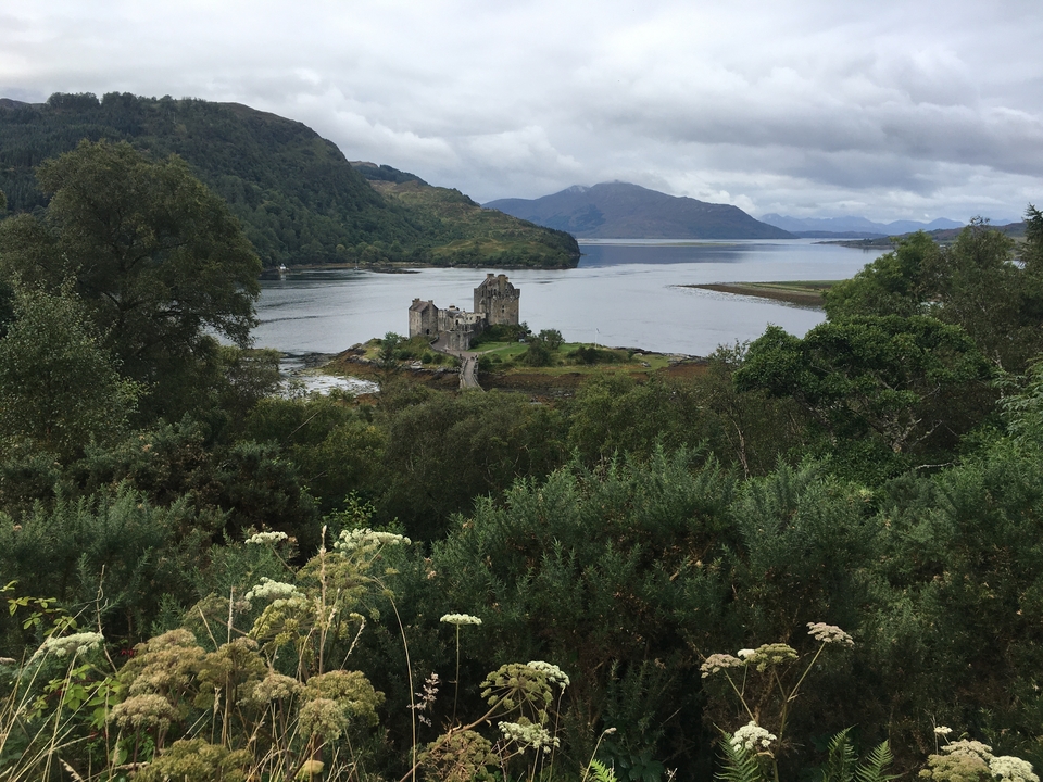 Un château entouré d'une végétation luxuriante avec vue sur un loch.