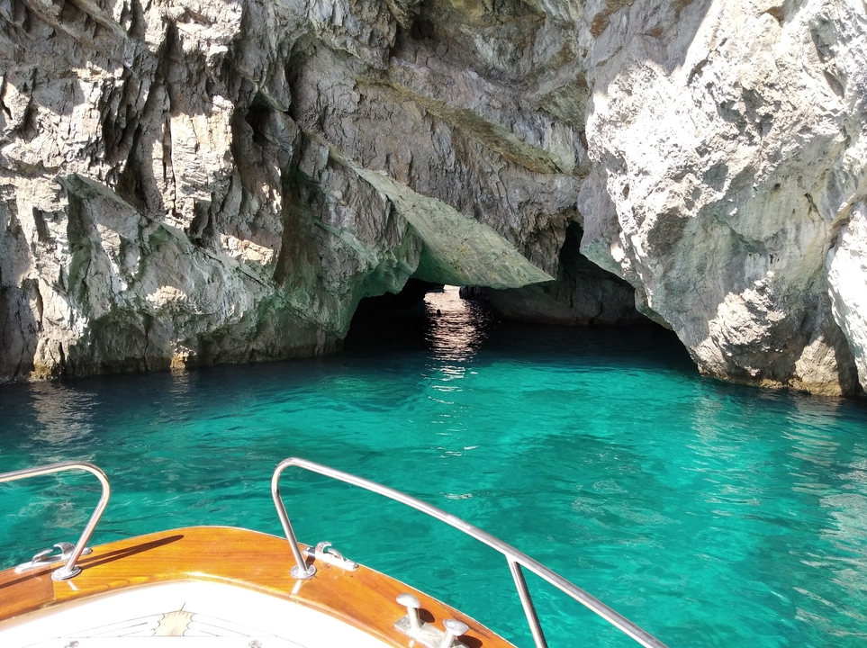Bateau entrant dans une grotte avec une eau bleue claire.