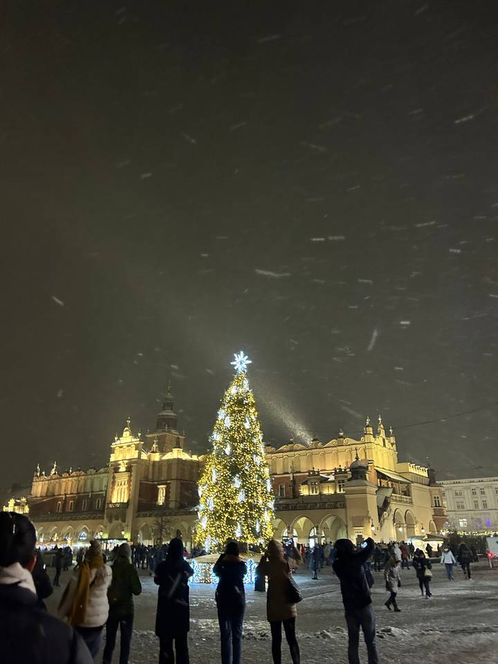 Sapin de Noël et scène de neige la nuit sur une place de ville.