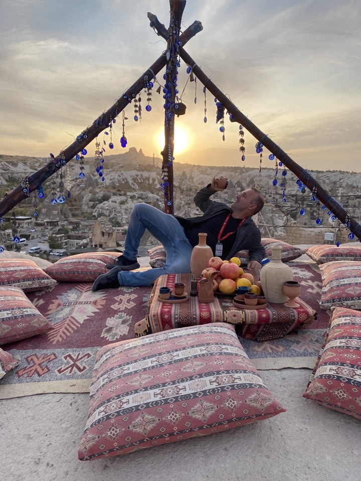 Homme profitant d'un cadre traditionnel avec vue sur la Cappadoce au coucher du soleil.