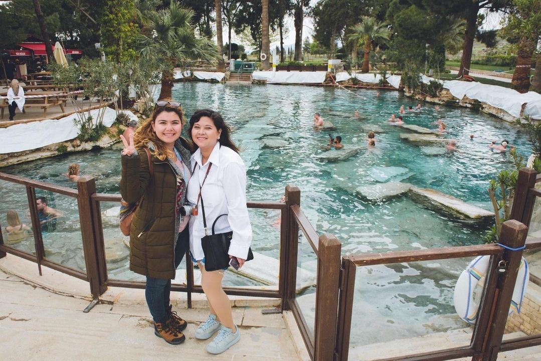 Two women pose beside the clear thermal waters of Cleopatra’s Pool in Pamukkale