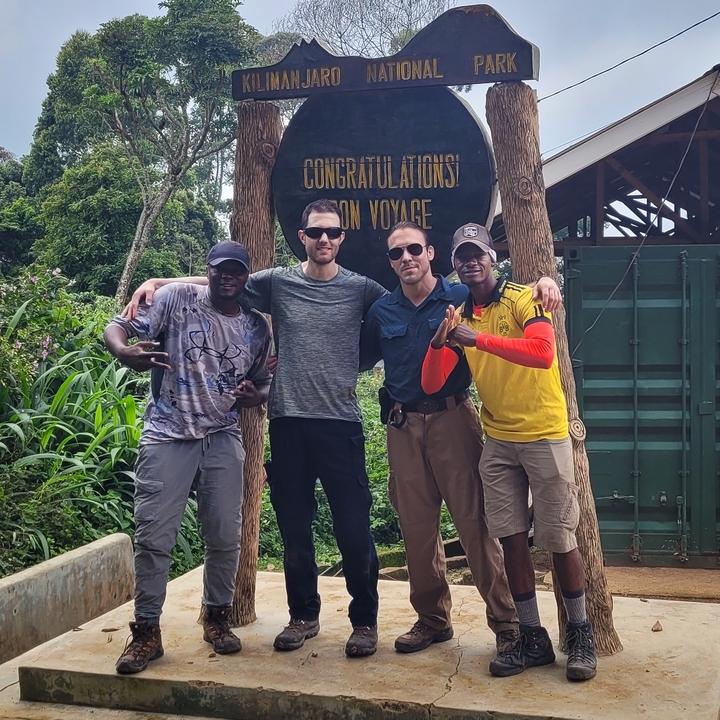 Groupe de personnes debout devant un panneau de bienvenue dans un camp.