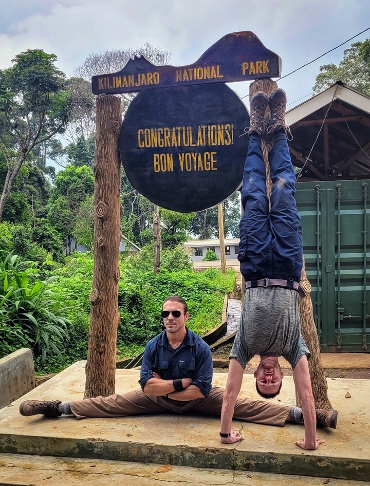 Personne posant la tête en bas à côté d'un panneau de bienvenue.