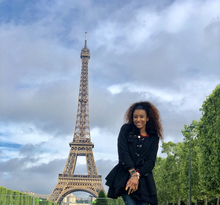 Woman smiling with the Eiffel Tower in the background.
