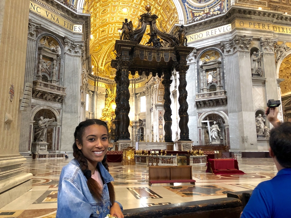 Woman inside a grand cathedral with ornate architecture.