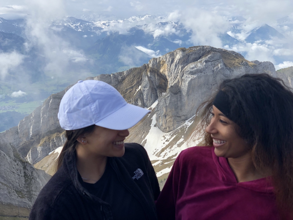 Two women smiling with a mountainous landscape behind them.