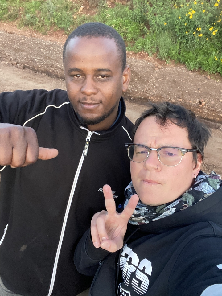 Casual selfie of guide and traveler flashing peace sign on a dusty road