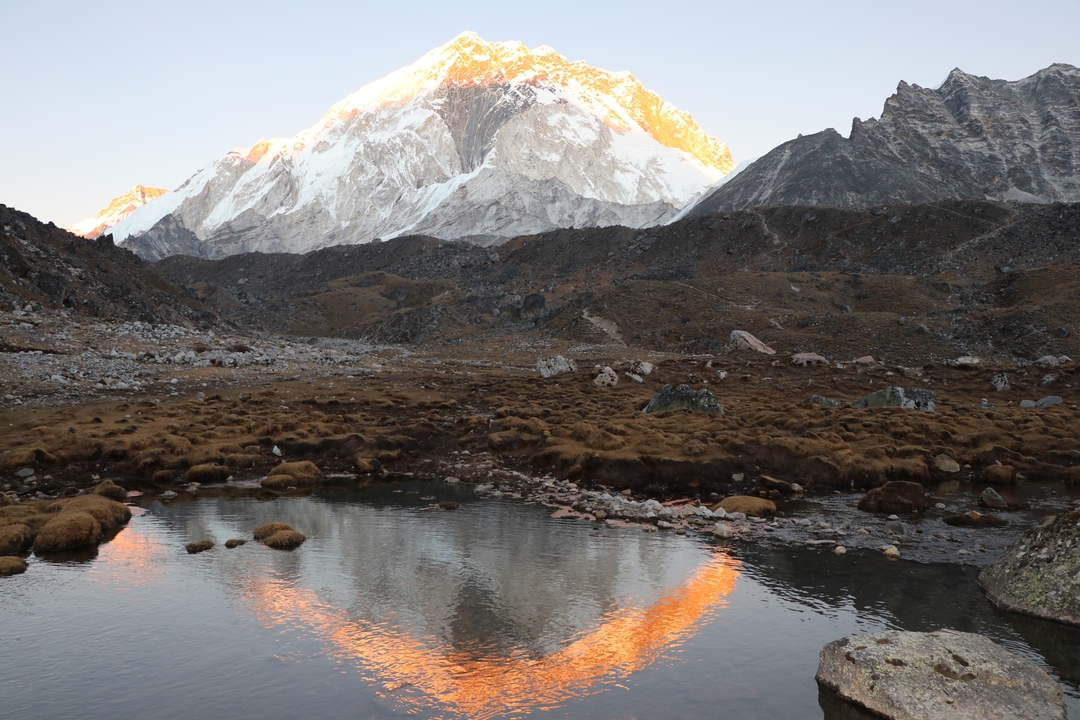 Mountain landscape with snow-capped peaks reflected in water.