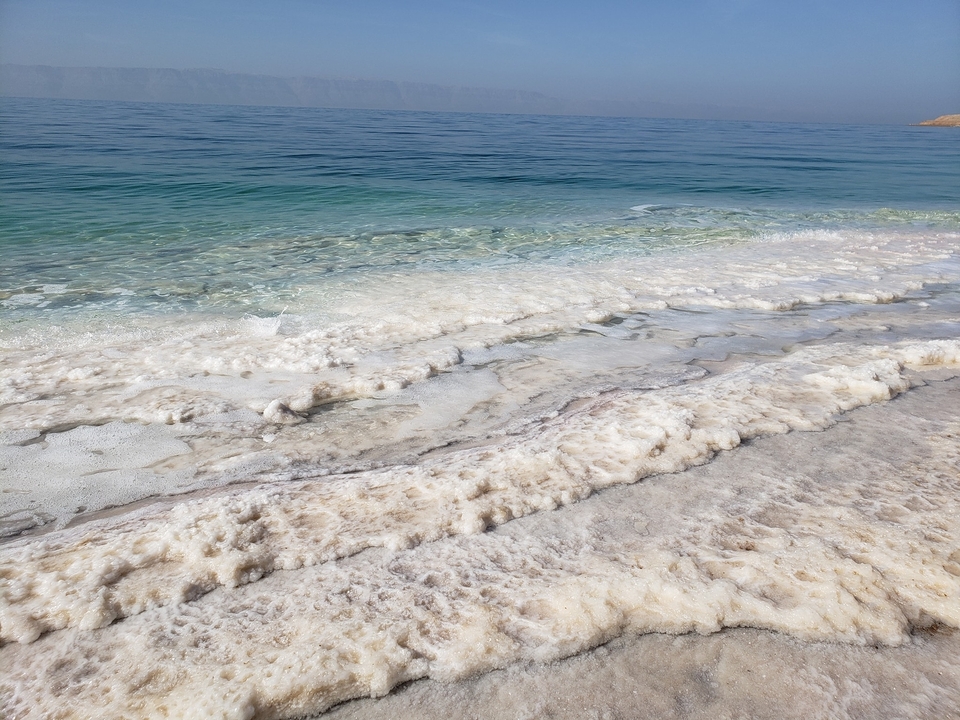Crystalline salt formations line the shore where turquoise waters meet the Dead Sea’s pale shoreline.