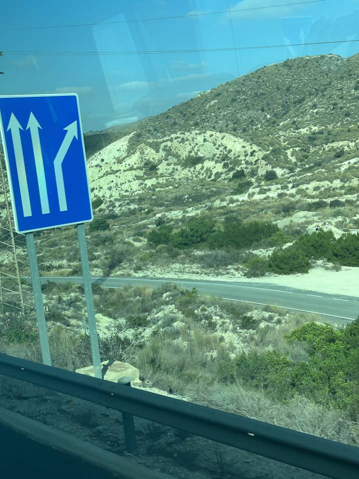 Deserted road with direction sign, hill backdrop.