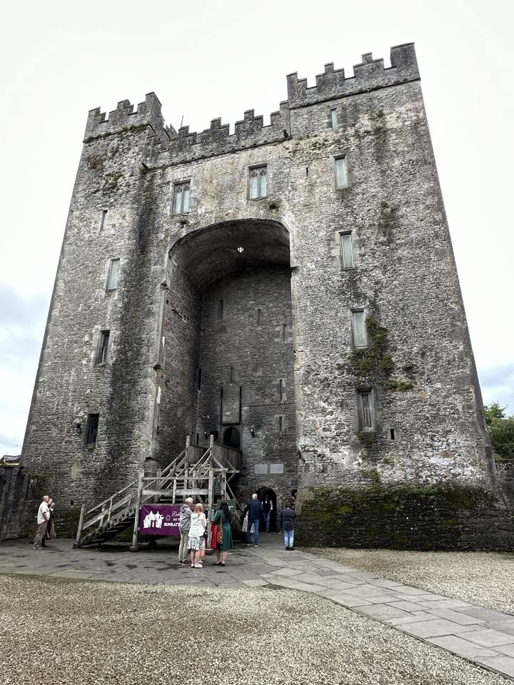 Une entrée de château en pierre avec des gens près de la porte.