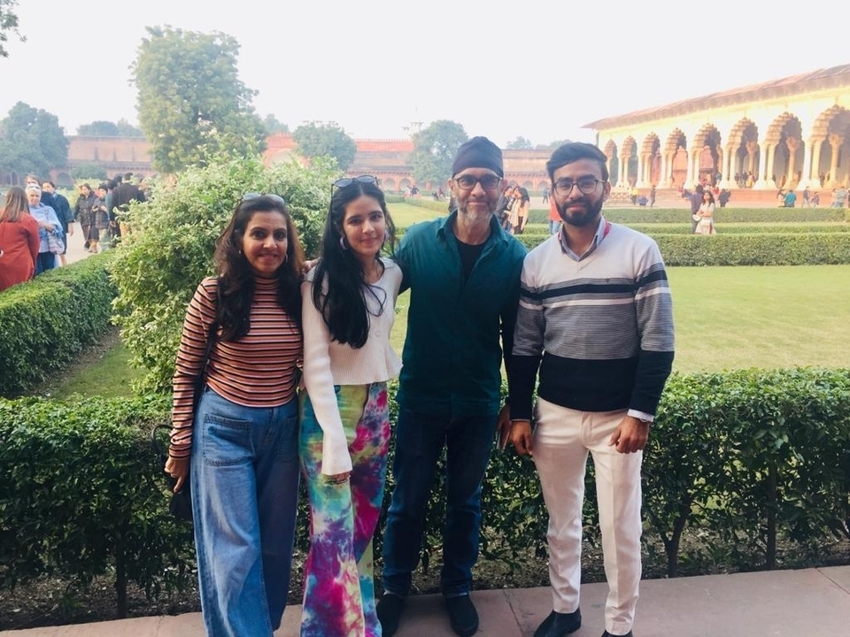 Quatre personnes posant dans un jardin avec une architecture historique en arrière-plan.