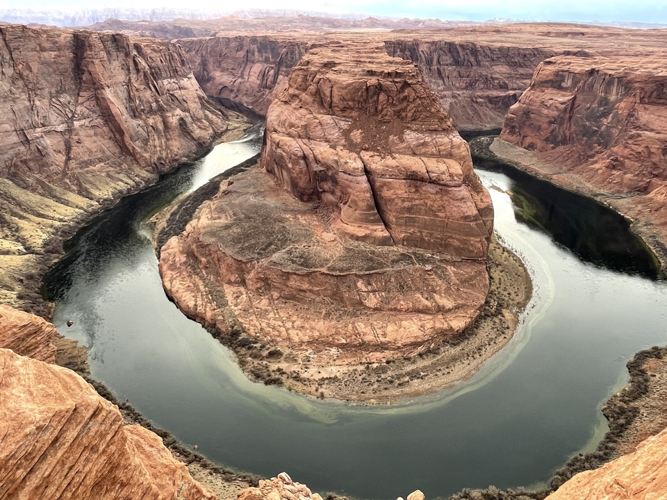 Vue aérienne d'une rivière serpentant autour d'une formation rocheuse dans un canyon.