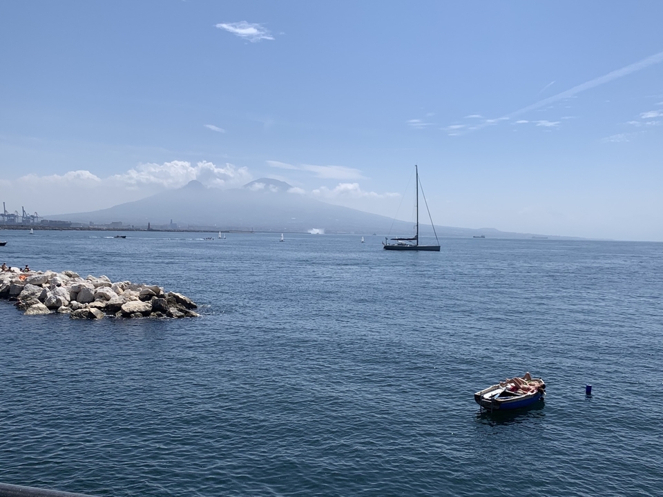 Segelboote auf einem ruhigen Meer mit einem Berg im Hintergrund.