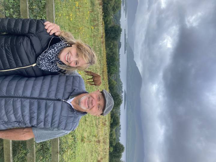 Couple souriant sur un décor de campagne avec des chevaux.