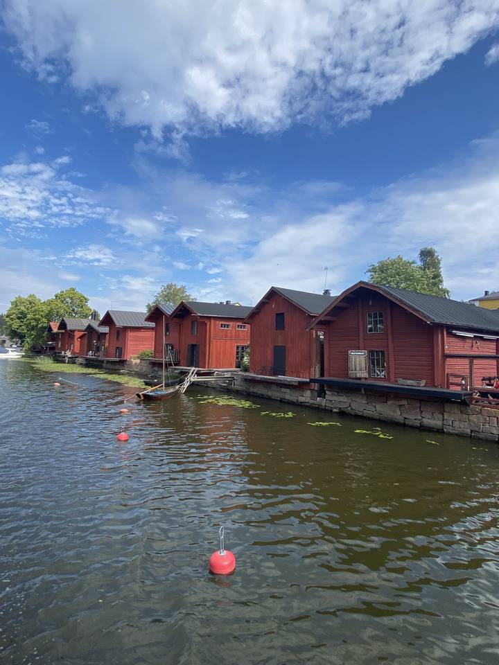 Maisons en bois rouge au bord de l'eau avec un ciel bleu.