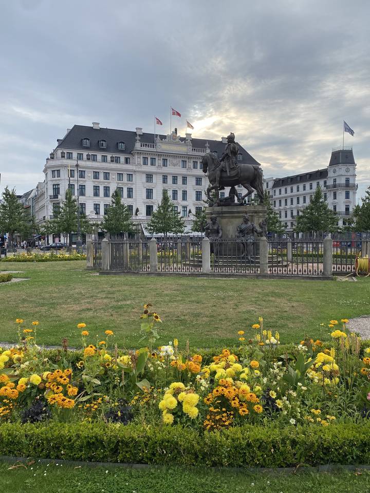 Statue équestre devant un bâtiment avec des drapeaux.