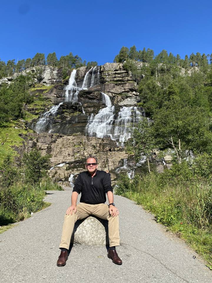 Homme assis près d'une cascade dans une région montagneuse.