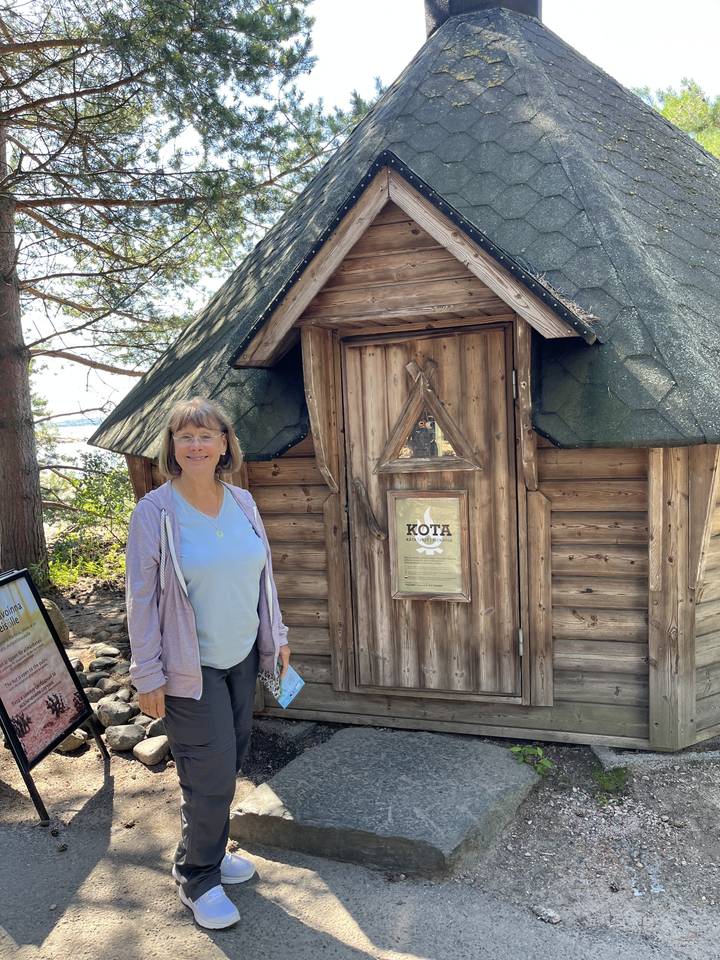 Personne debout à côté d'une petite structure en bois avec un panneau.