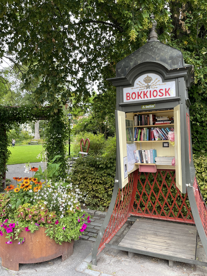 Kiosque à livres ouverts dans un jardin avec des fleurs.