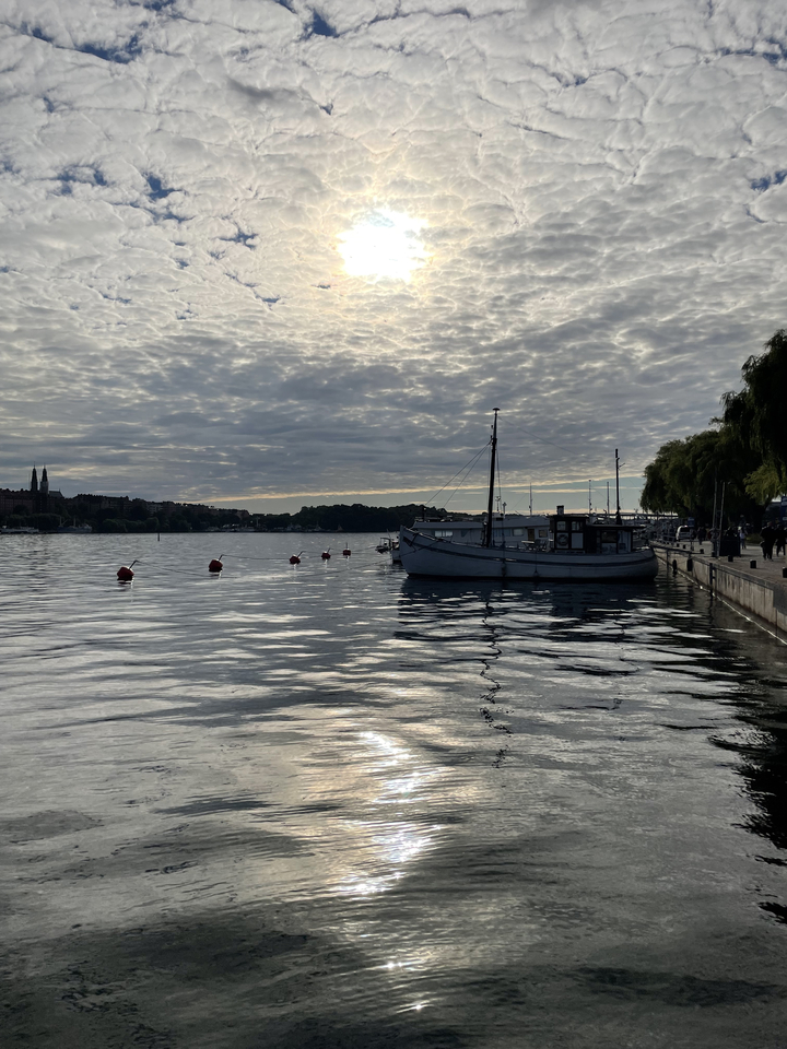 Bateau amarré à un front de mer avec un ciel nuageux.