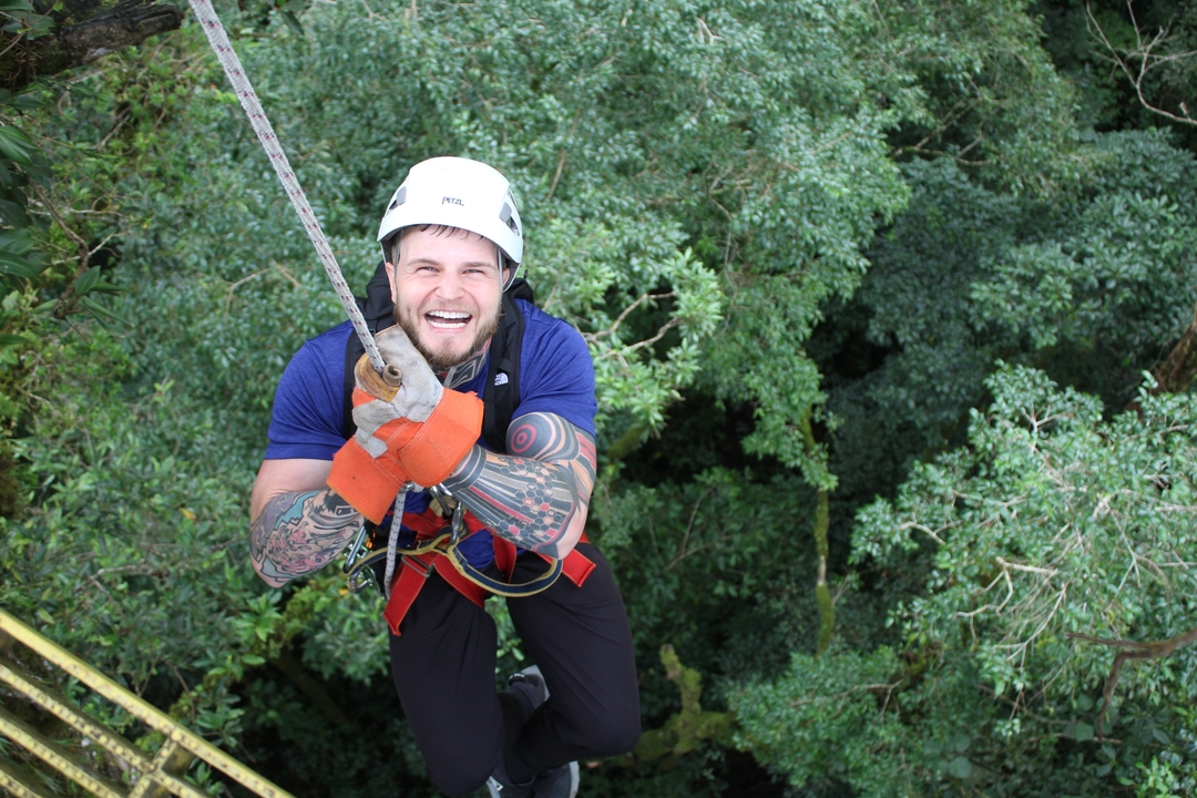 Personne faisant de la tyrolienne à travers une forêt dense.