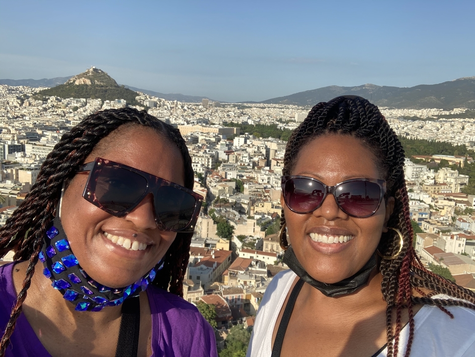 Deux personnes avec un paysage urbain d'Athènes en arrière-plan.