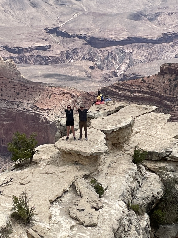 Deux personnes debout sur un rebord rocheux surplombant un canyon.