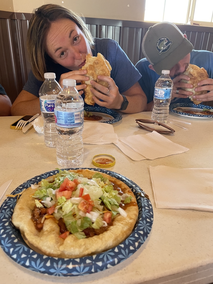 Des gens qui mangent à une table avec des tacos et des bouteilles d'eau.