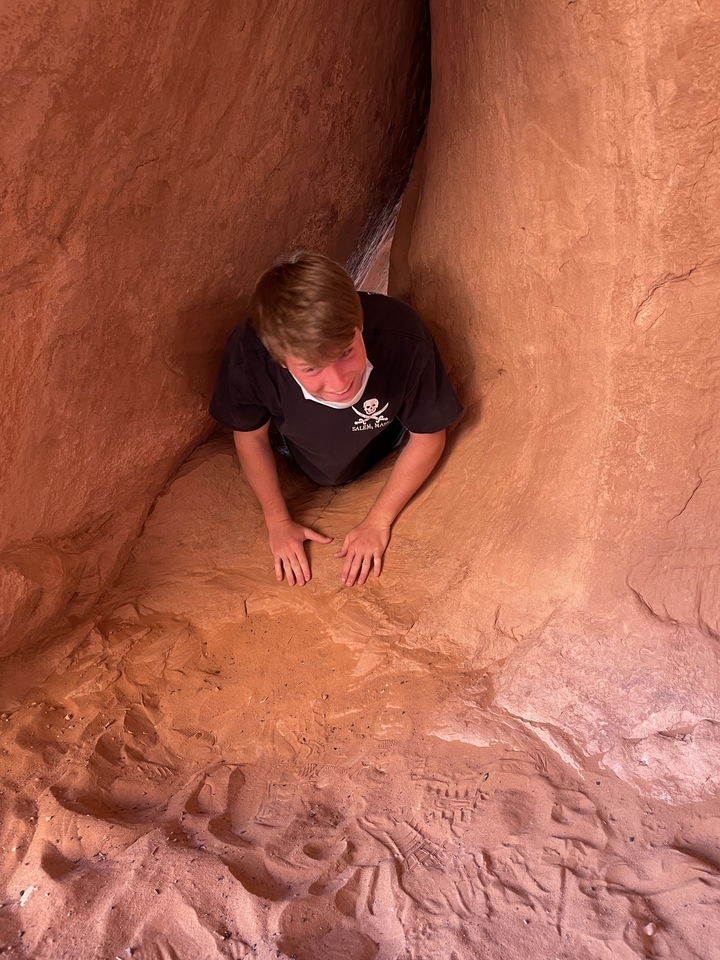 Personne se faufilant à travers une formation rocheuse étroite.