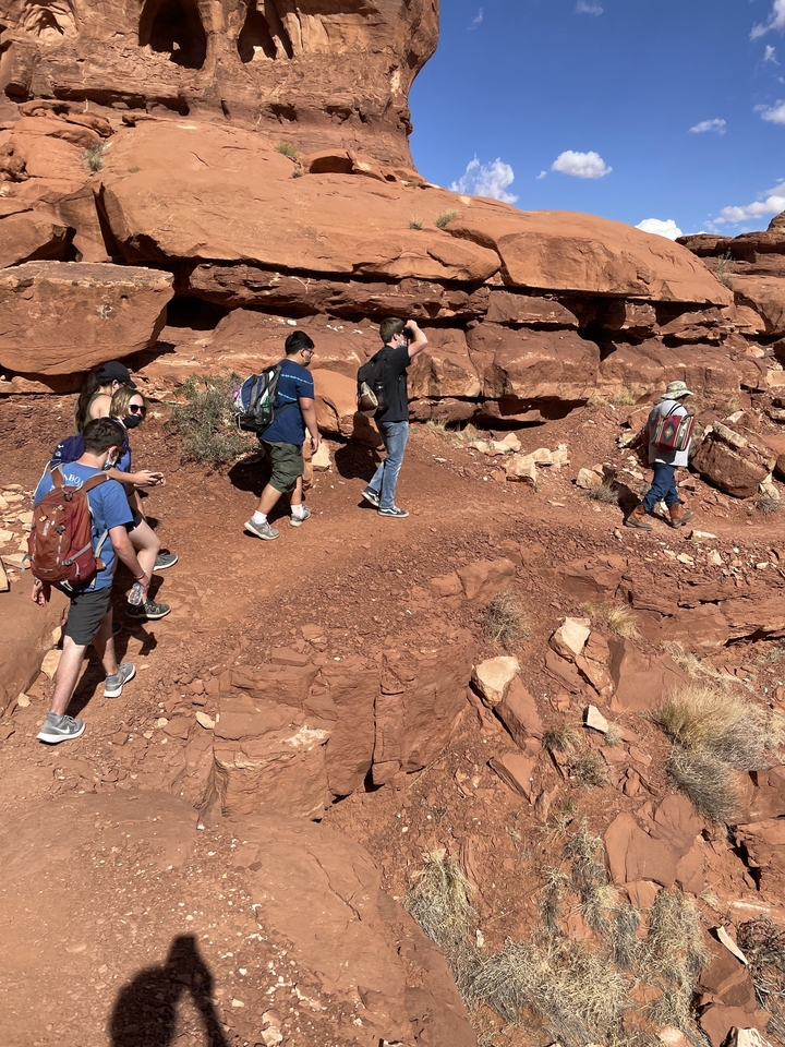 Groupe de randonneurs marchant le long d'un sentier de roches rouges.