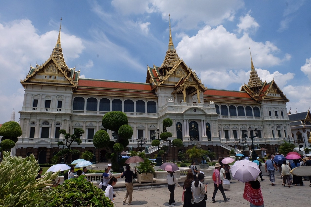 Un grand palais avec des touristes portant des parapluies.