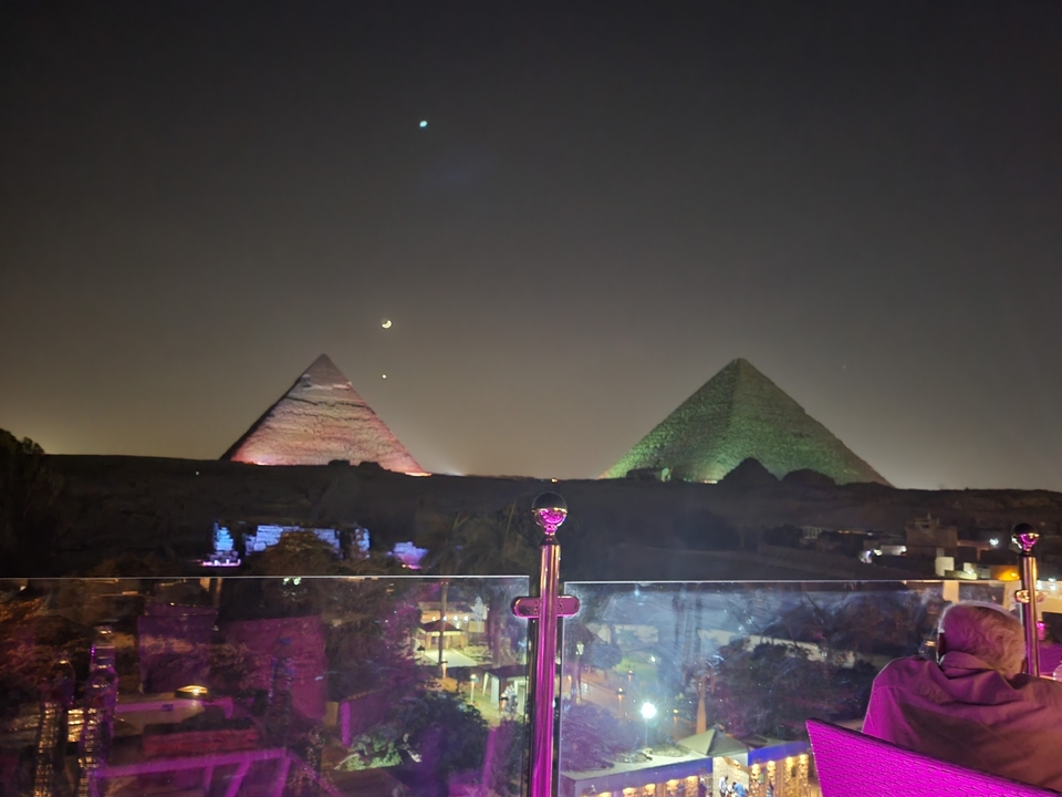 Pyramides illuminées la nuit avec des étoiles visibles dans le ciel.
