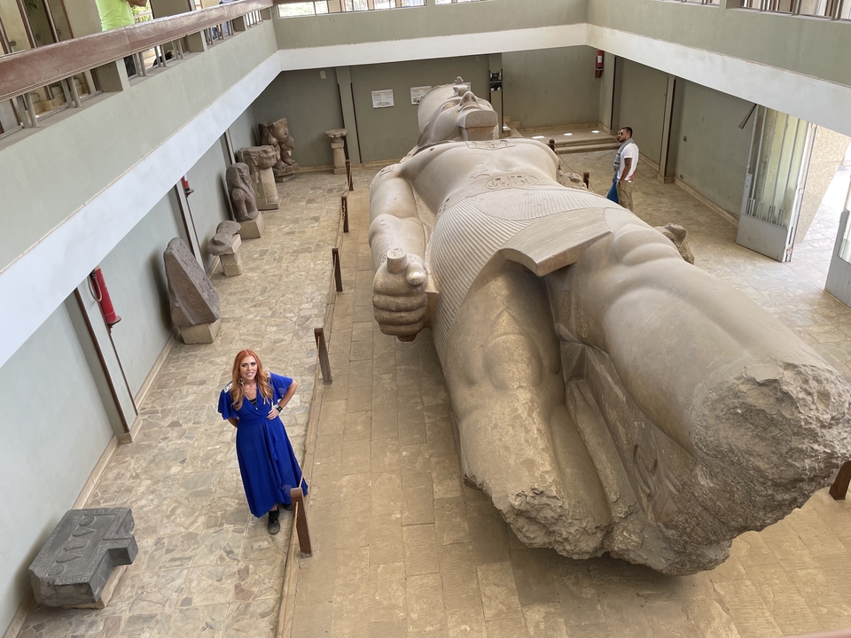 Personne debout à côté d'une grande statue allongée dans un musée.