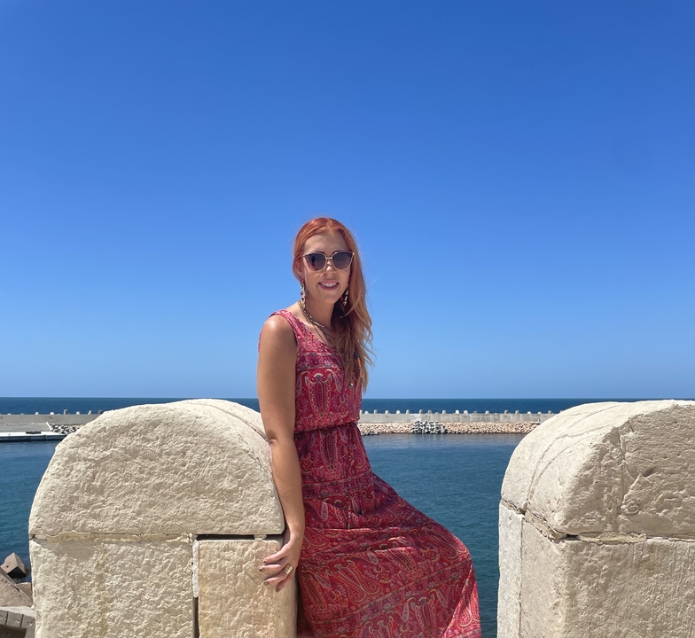 Personne assise au bord de la mer avec un port en arrière-plan.