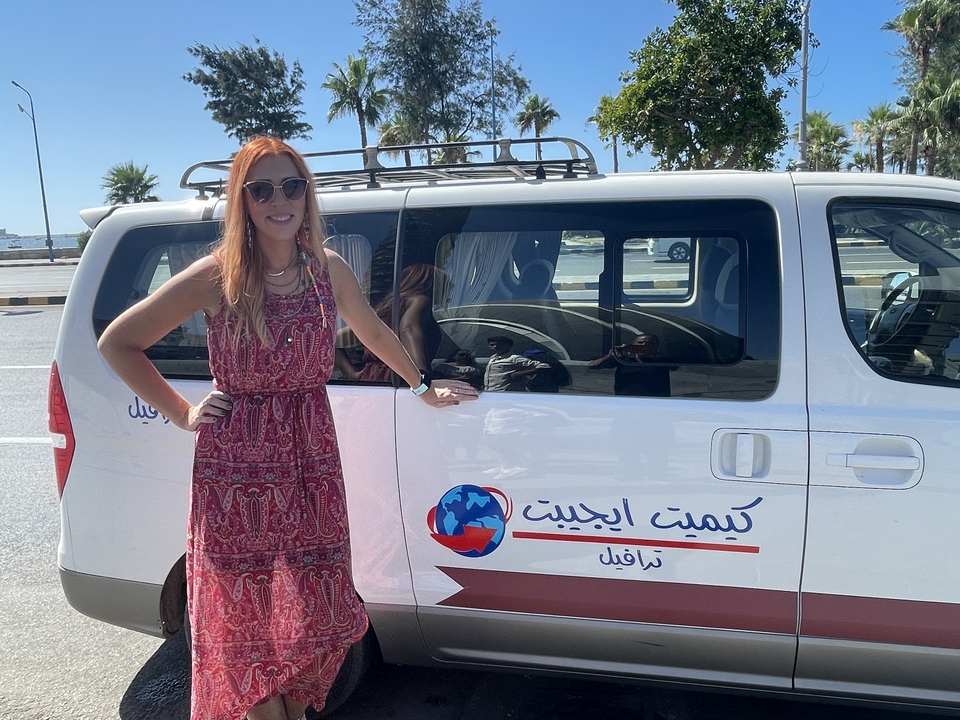 Personne debout à côté d'un van de tourisme avec de l'écriture arabe.