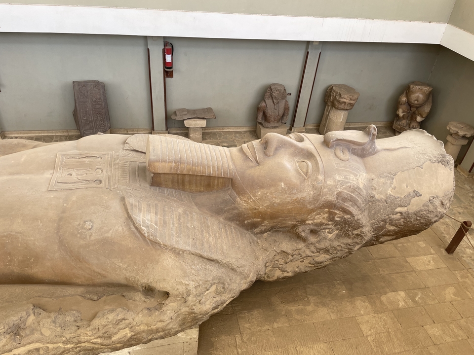 Grande statue couchée d'un pharaon exposée à l'intérieur.