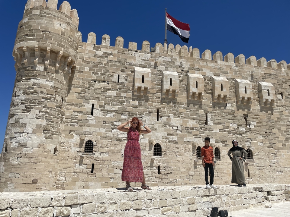 Personne debout devant un fort historique avec un drapeau au sommet.