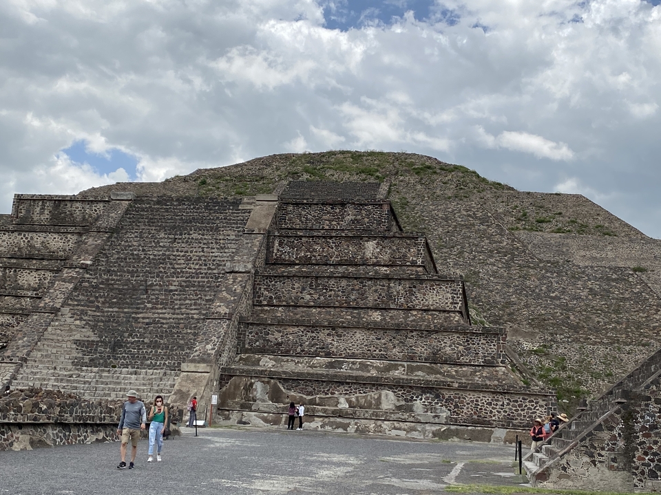Grande pyramide de pierre avec des touristes qui montent les marches.