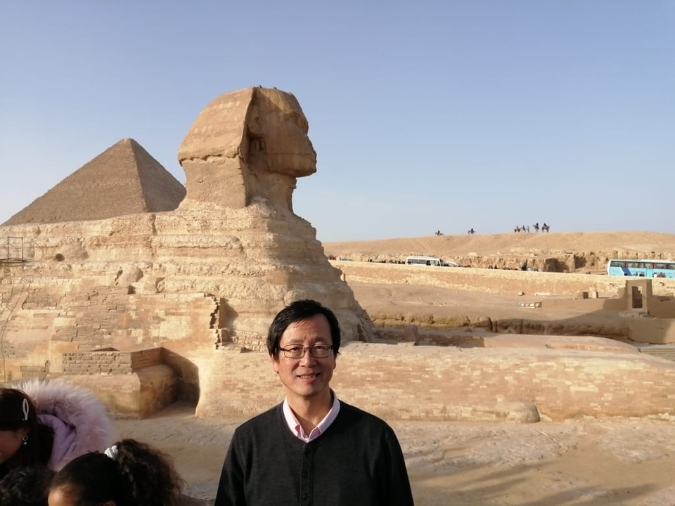 Touriste posant devant le Sphinx et une pyramide.