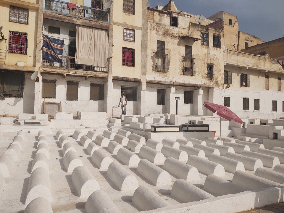 Personne marchant près de structures en pierre blanche devant de vieux bâtiments.