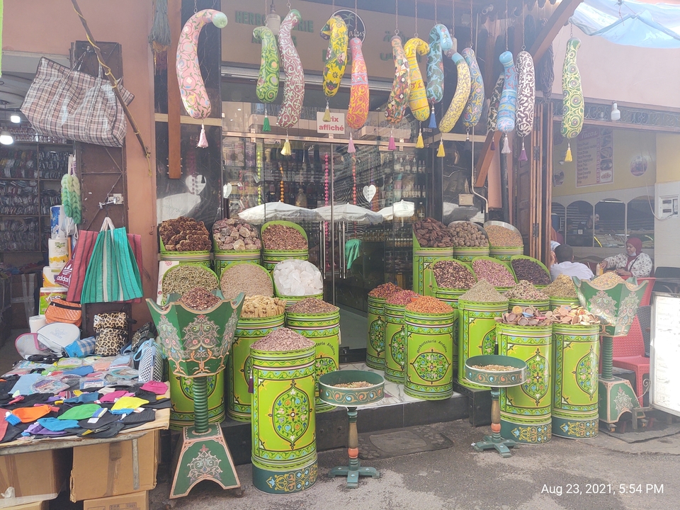 Devanture de magasin présentant des épices colorées dans des récipients décoratifs.