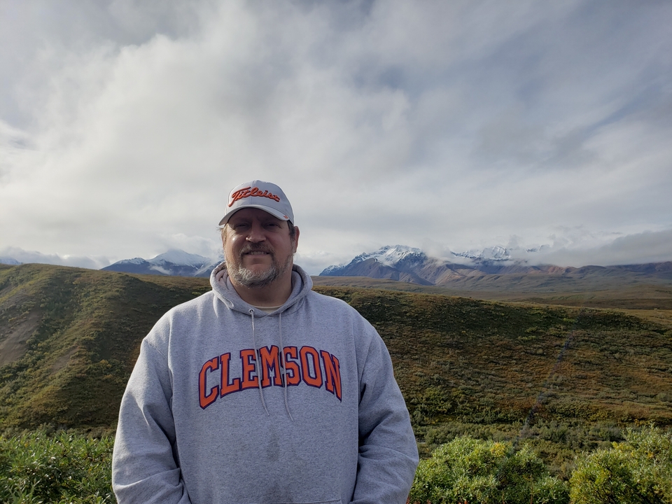 Personne debout dans un paysage avec des montagnes en arrière-plan.