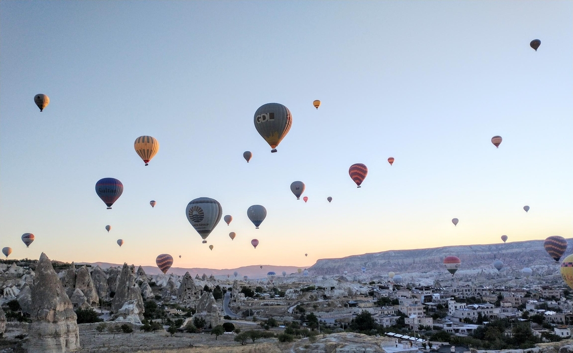 Montgolfières en vol au-dessus d'un paysage rocheux au lever du soleil.